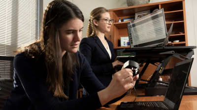  Brinnae Bent (foreground), during her time as a PhD student, preparing to download information from a wearable health monitoring device, with Duke BME faculty member Jessilyn Dunn.